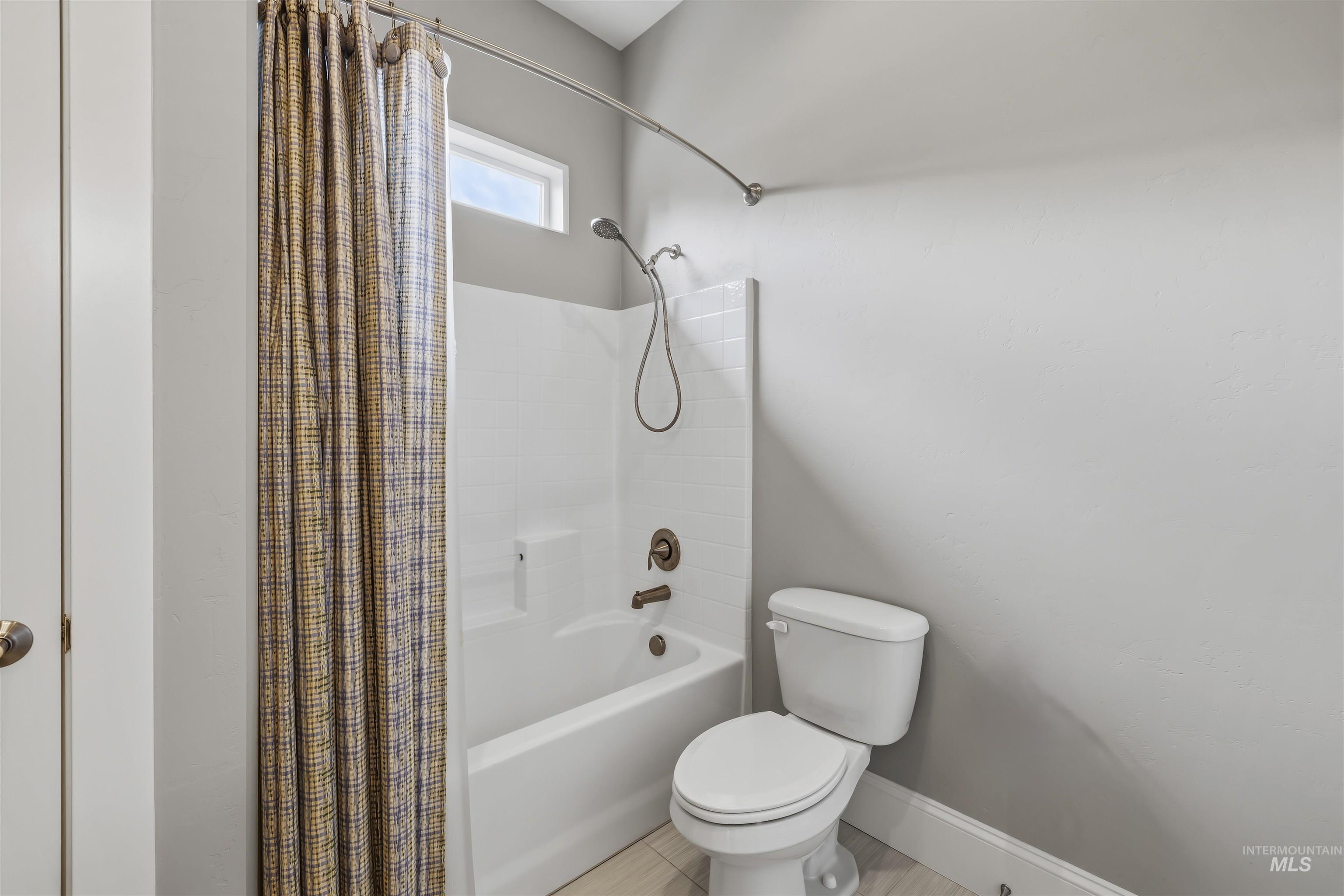 Tub and shower combination with subway tile surround, bronze fixtures, and a high transom window
