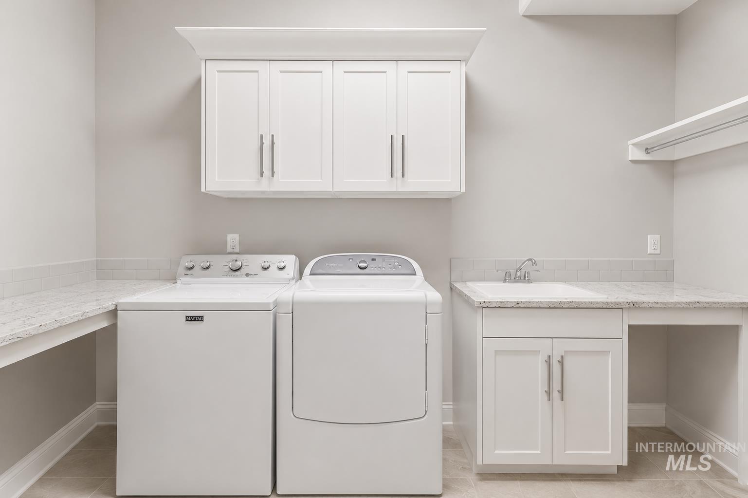 Laundry room featuring white shaker cabinetry, an integrated utility sink, light-toned countertop, and subway tile backsplash