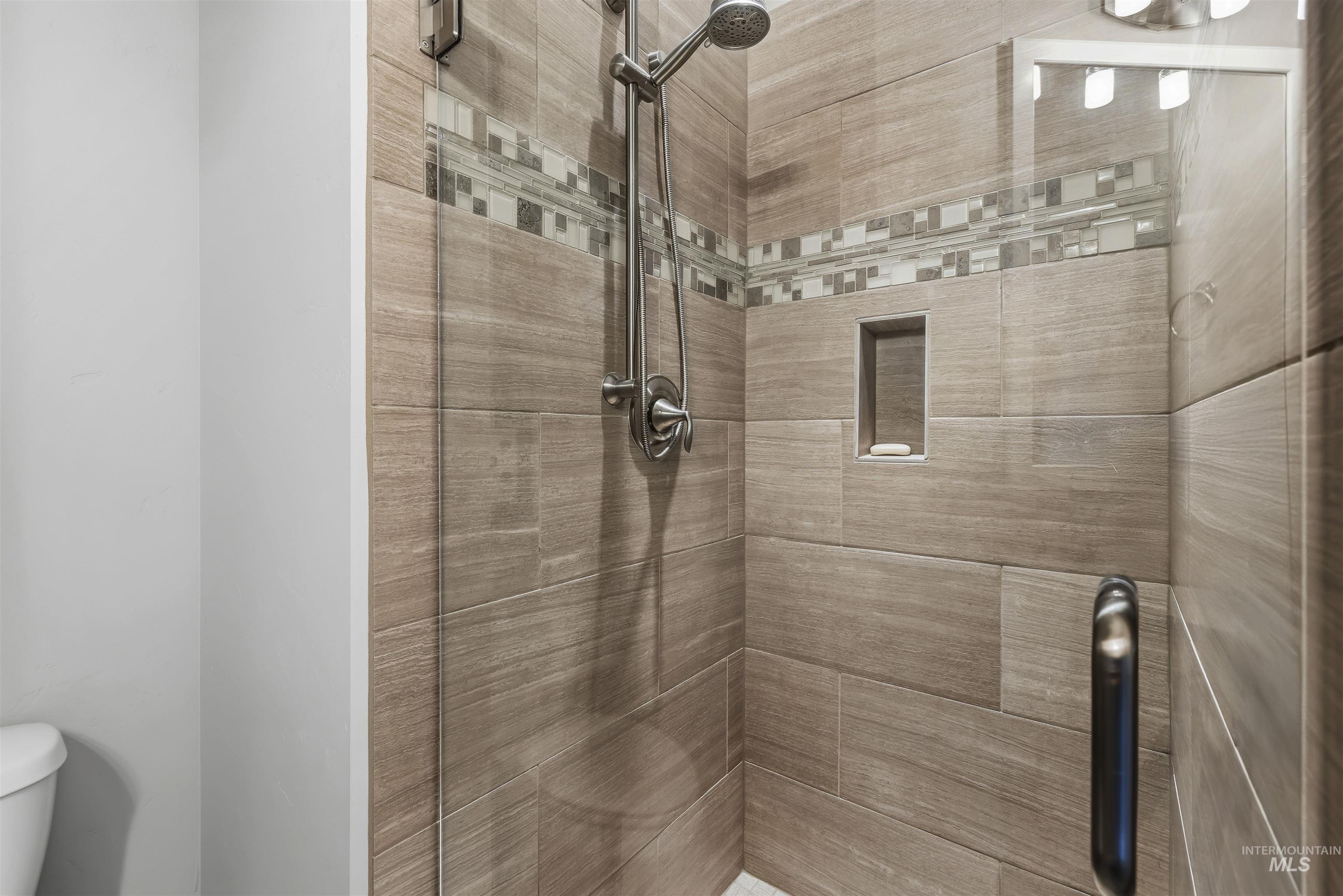 Walk-in shower with wood-finish tile and glass mosaic accent band
