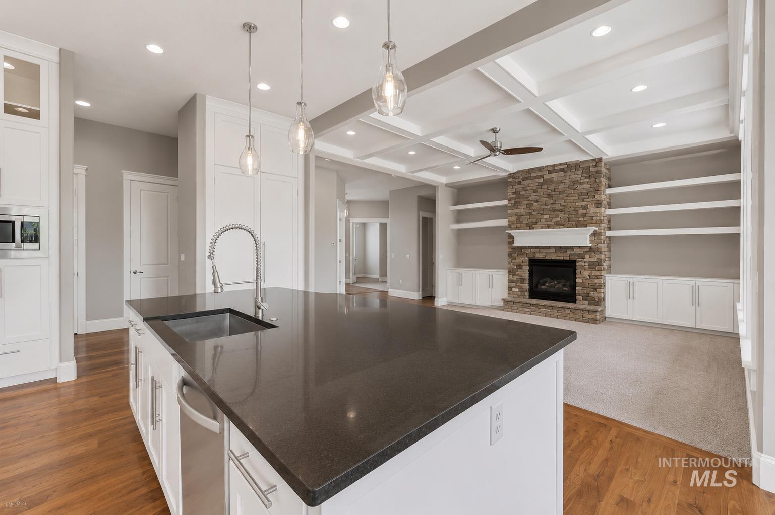 Kitchen island with a dark countertop and undermount sink, complemented by pendant lighting