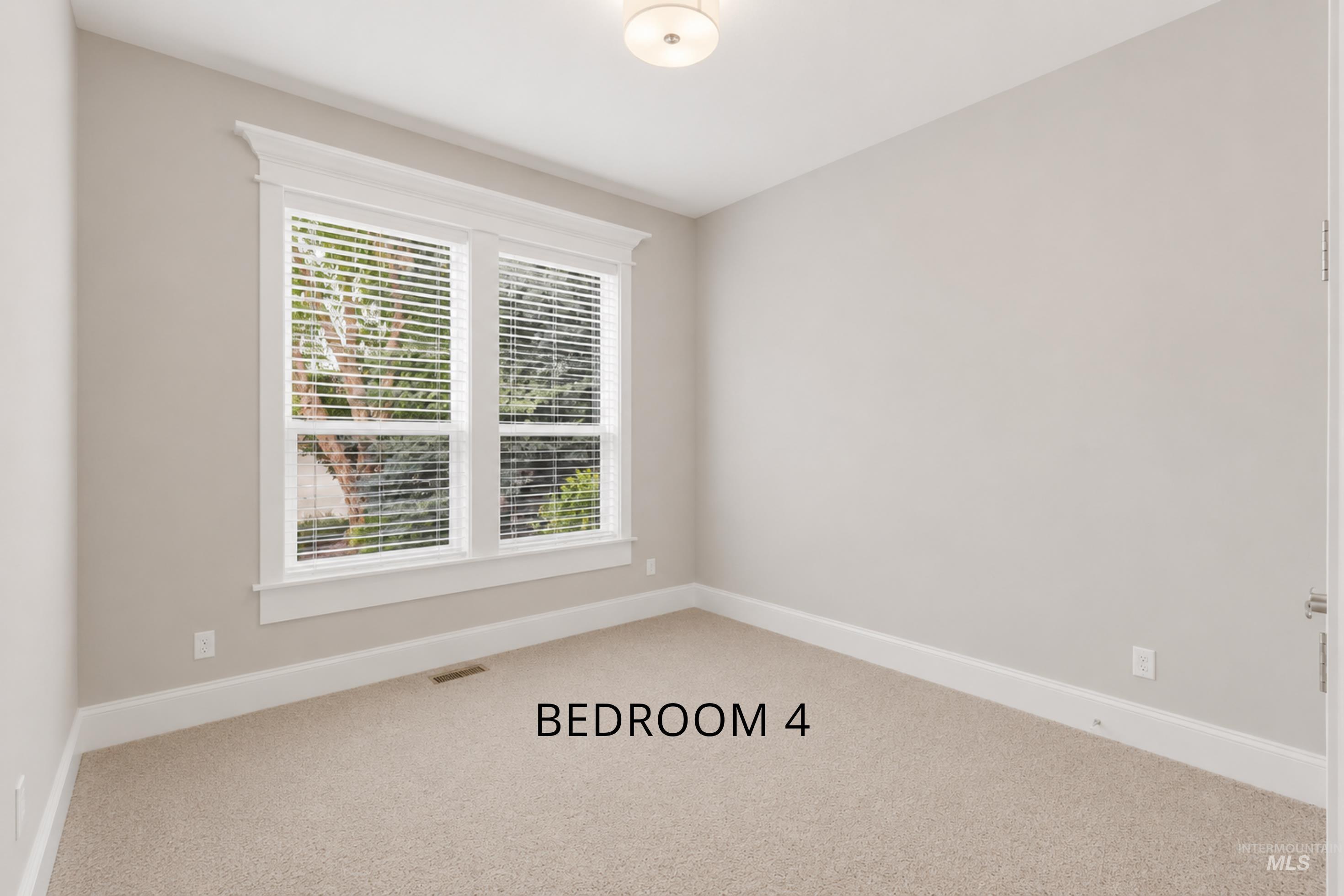 Bright bedroom featuring a large window with blinds, neutral carpeting, and light wall paint