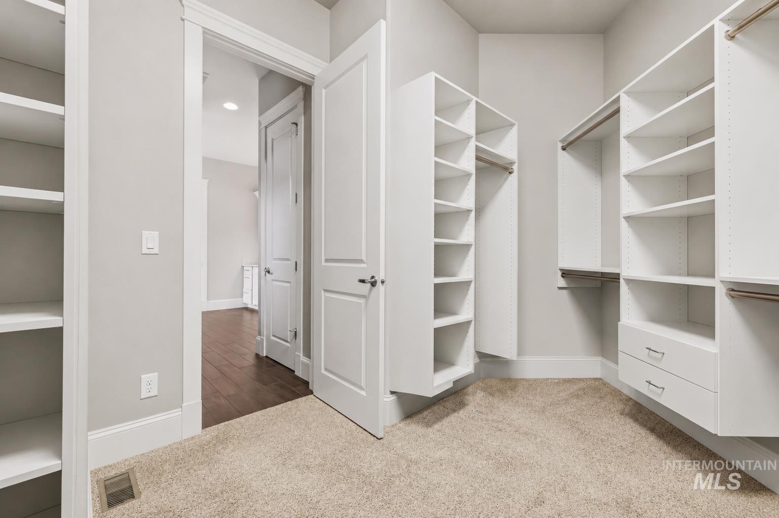 Expansive walk-in closet featuring extensive built-in shelving, hanging rods, and integrated drawers