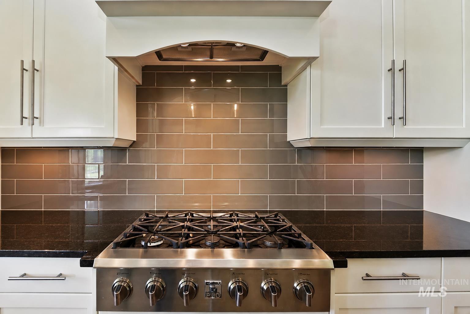Stainless steel range with a built-in ventilation hood, complemented by white shaker-style cabinetry