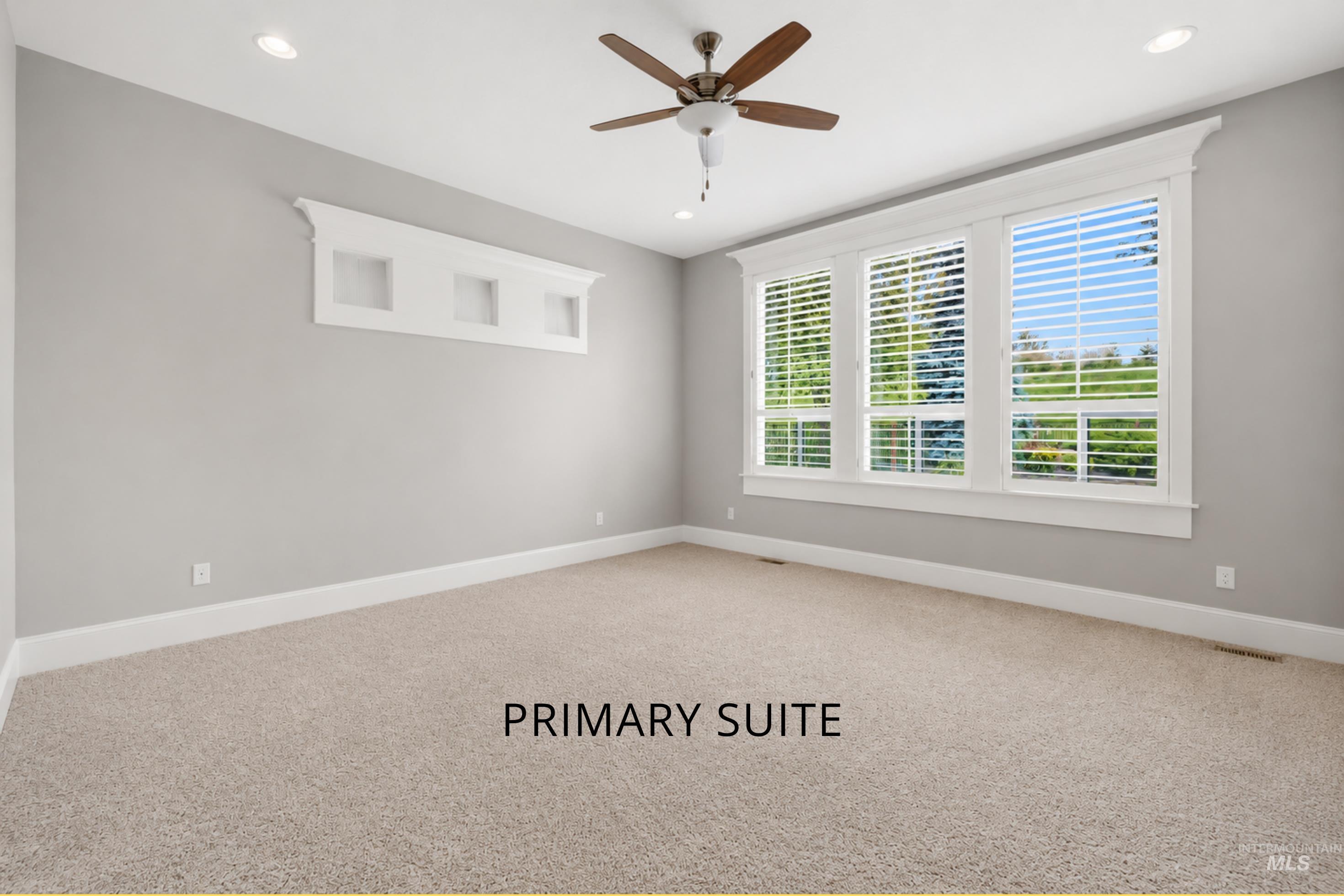 Spacious carpeted room featuring a three-panel window with white blinds, a decorative wall niche, a ceiling fan, and recessed lighting