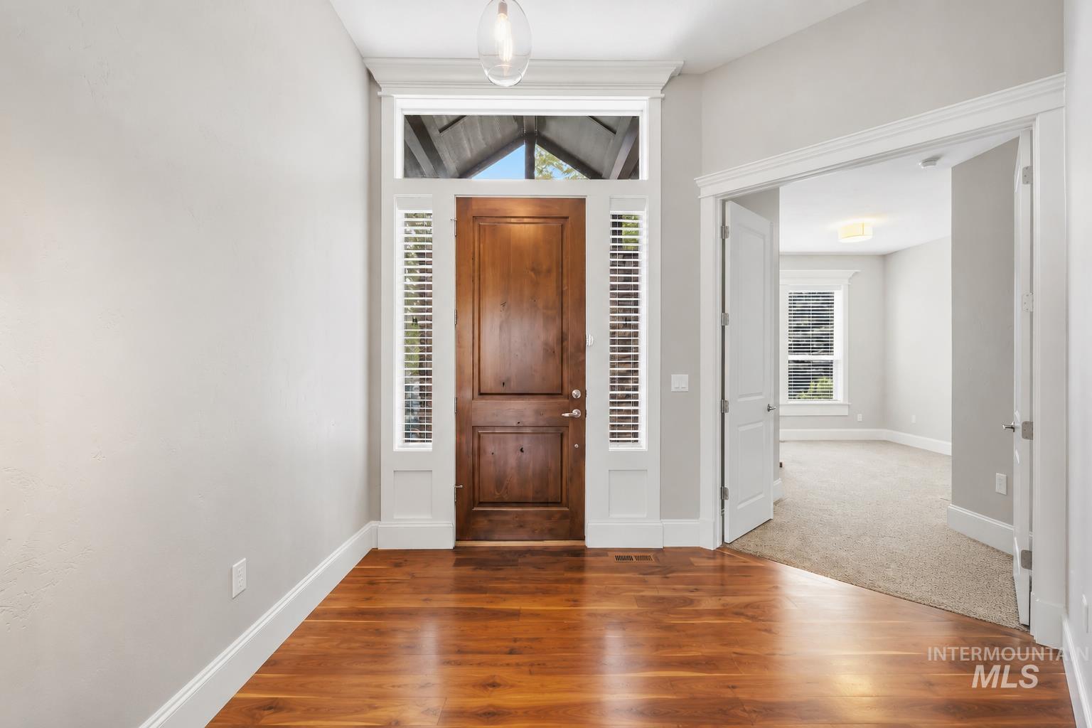 Entryway featuring wood-finish flooring, a solid wood entry door with sidelights and transom window, and a glass pendant light fixture
