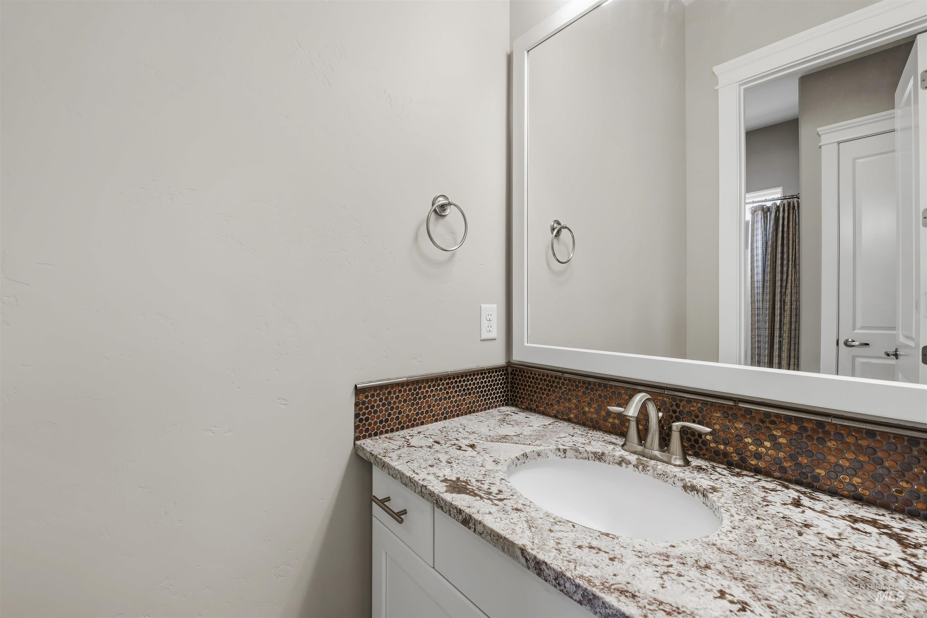 Vanity featuring a white oval undermount sink, brushed nickel faucet, and a granite countertop