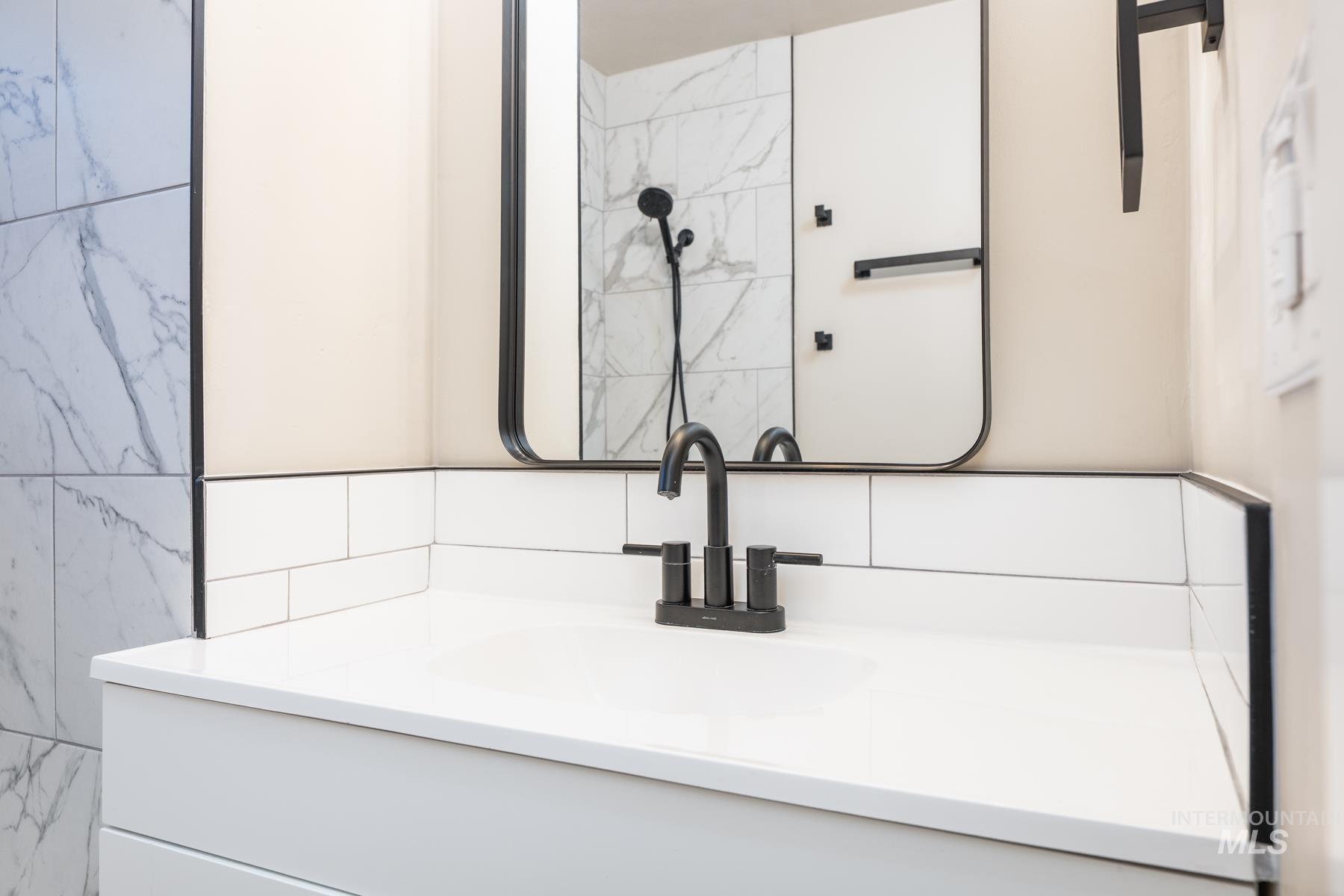 Bathroom view of vanity, tile walls, and decorative backsplash