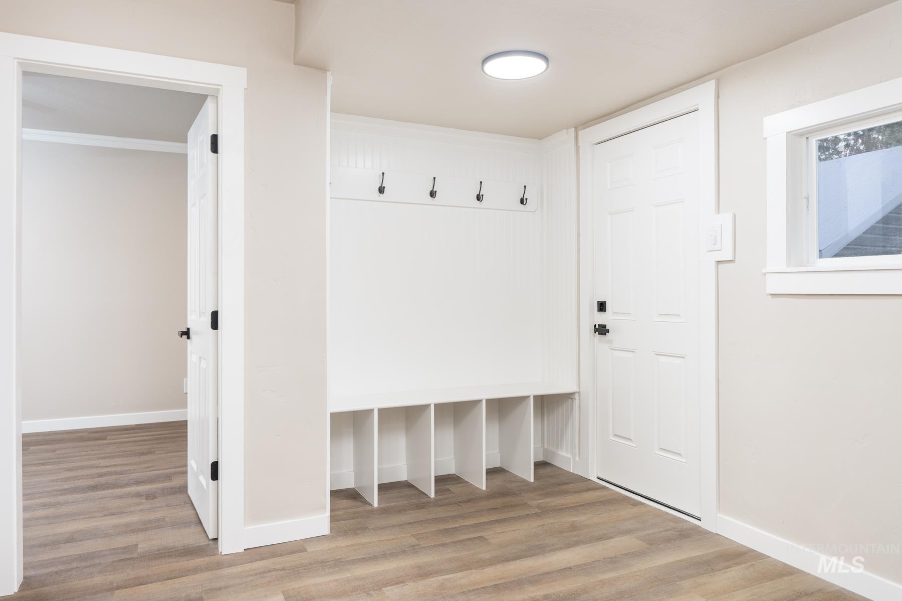 Mudroom with light wood-type flooring and ornamental molding