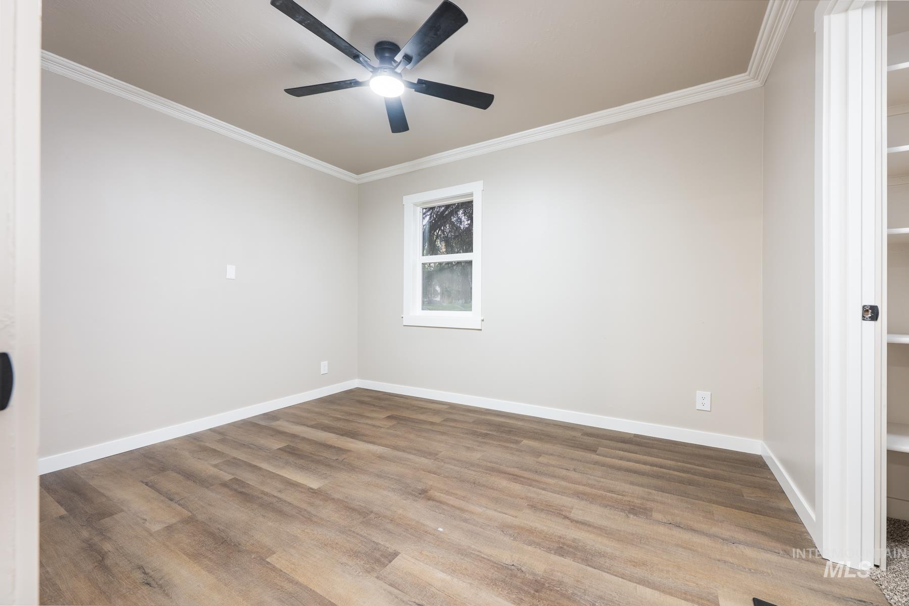 Empty room with ornamental molding and wood finished floors