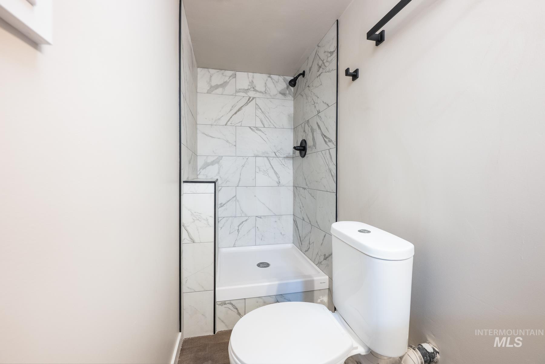 Full bathroom featuring a tile shower and toilet