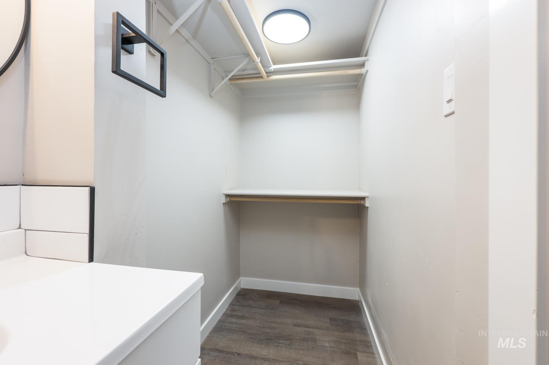 Walk in closet featuring dark wood-type flooring