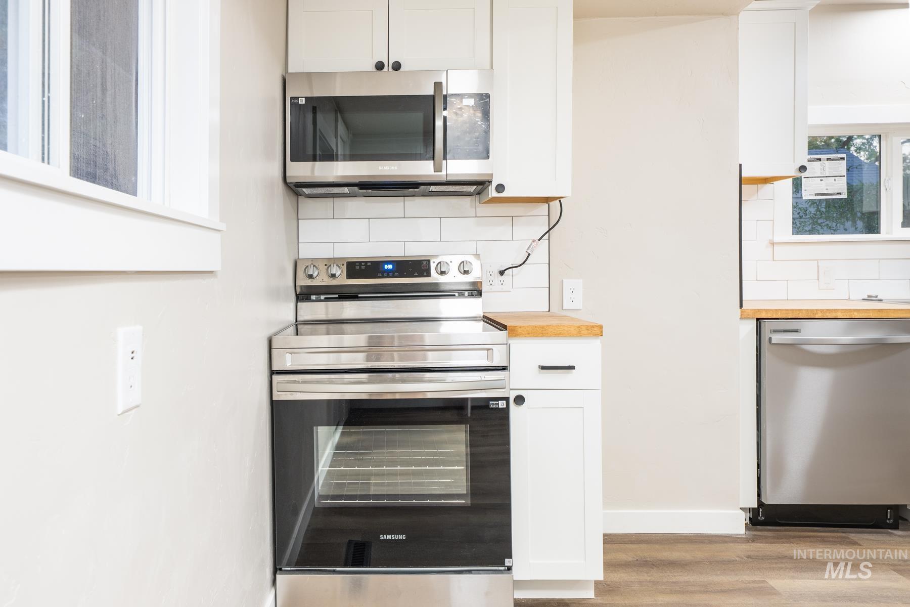 Kitchen featuring stainless steel appliances, white cabinets, and decorative backsplash