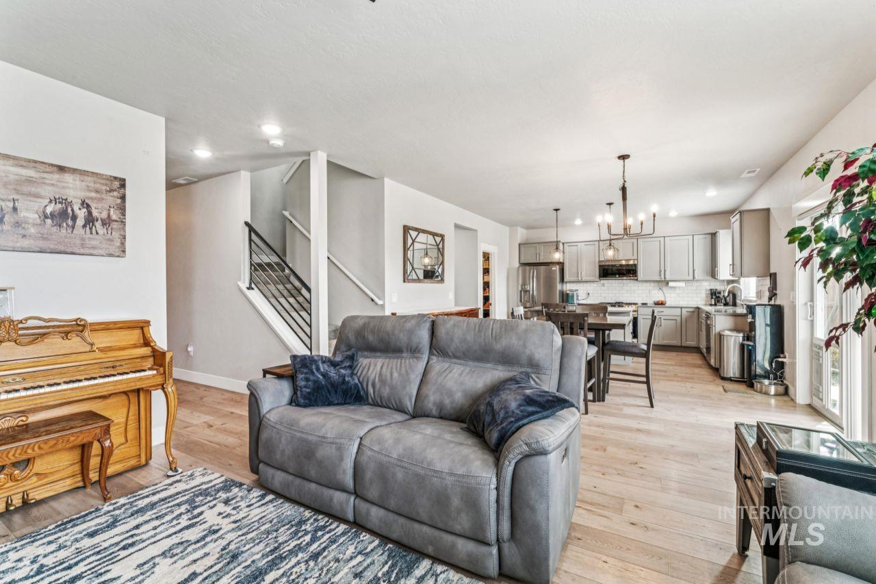 Living area with a chandelier, light wood-type flooring, stairs, and recessed lighting