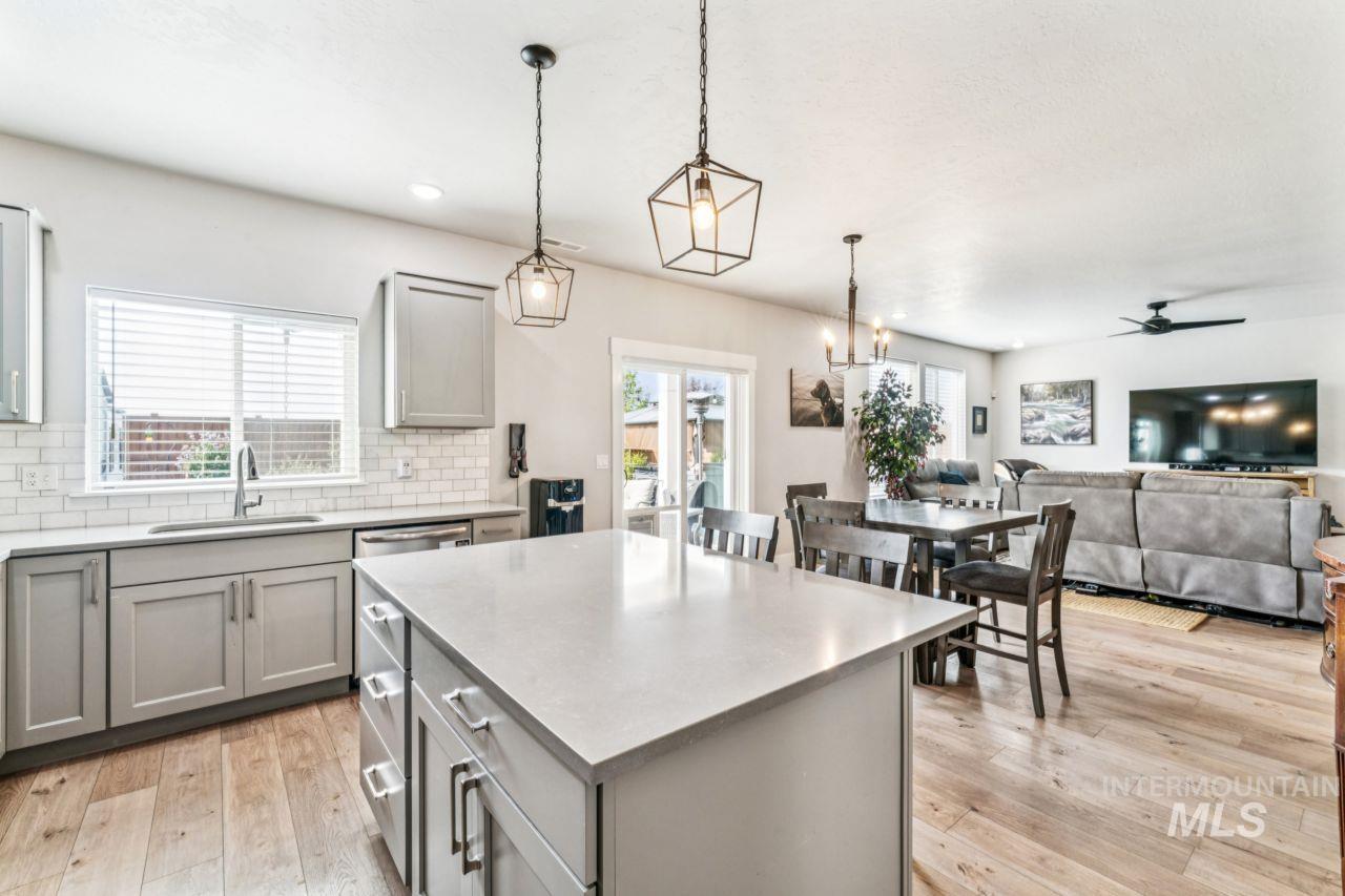 Kitchen with gray cabinets, a kitchen island, decorative light fixtures, and light wood finished floors
