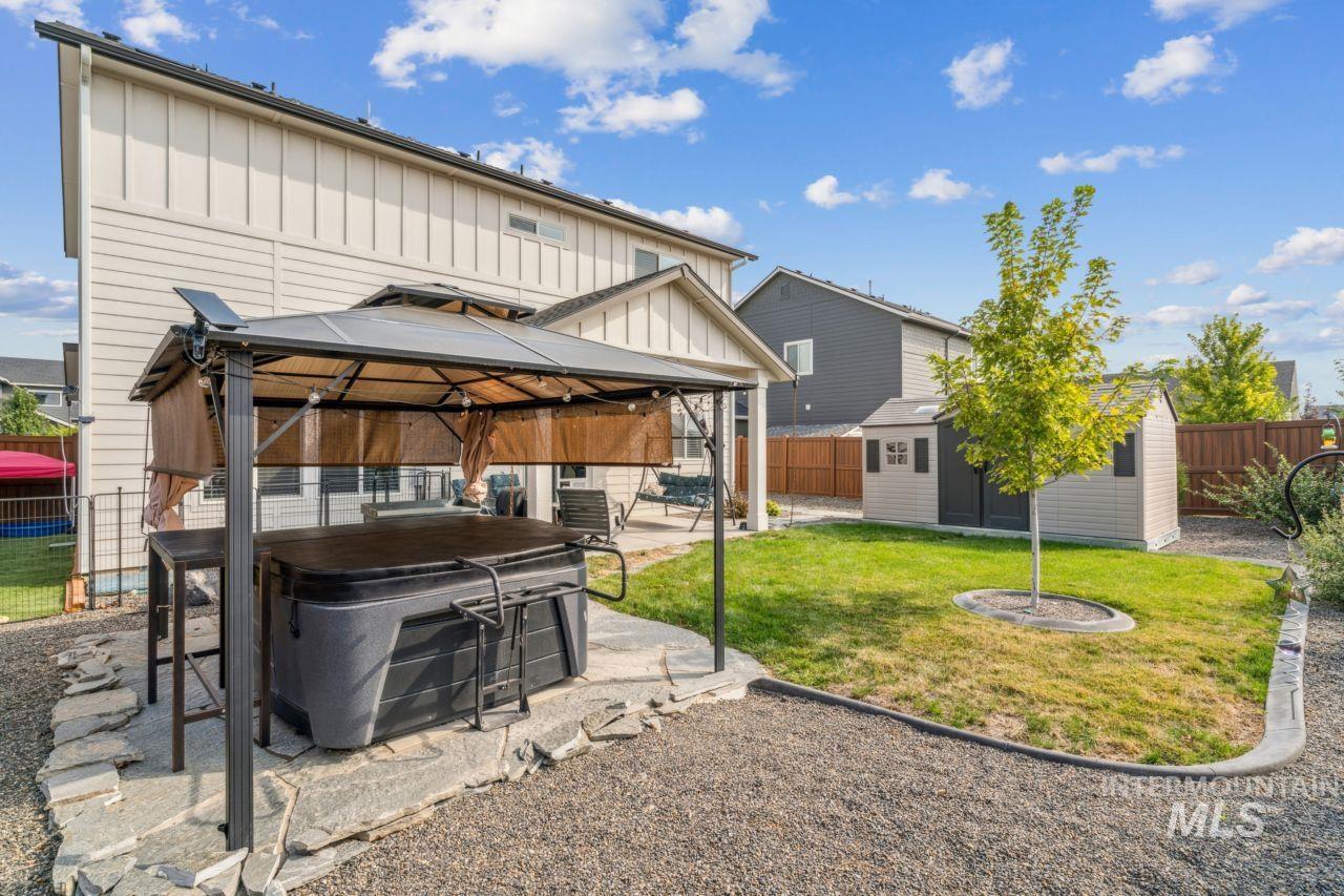 Back of property with board and batten siding, a gazebo, a fenced backyard, a patio, and a shed