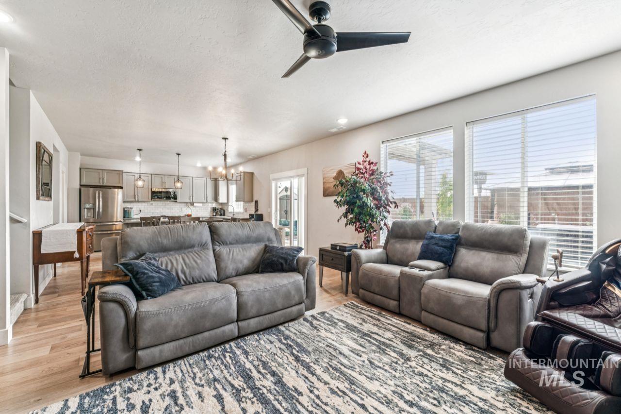 Living area with wood finished floors, a chandelier, a ceiling fan, and a textured ceiling