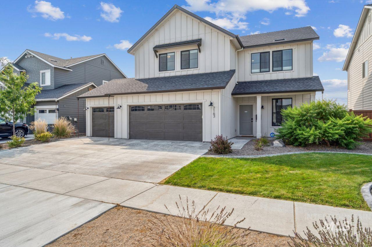 Modern farmhouse style home with board and batten siding, a shingled roof, concrete driveway, a front lawn, and a porch