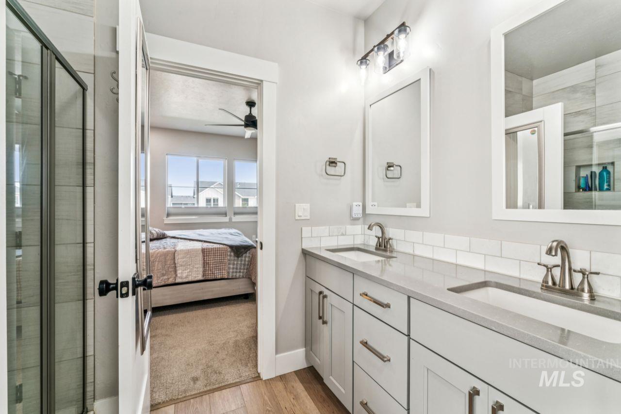 Bathroom with a shower stall, light wood-style floors, double vanity, connected bathroom, and ceiling fan