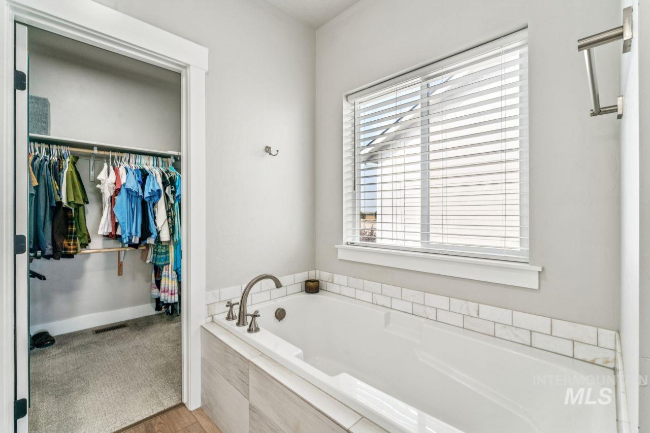 Full bath with a garden tub, a walk in closet, and light wood-style flooring