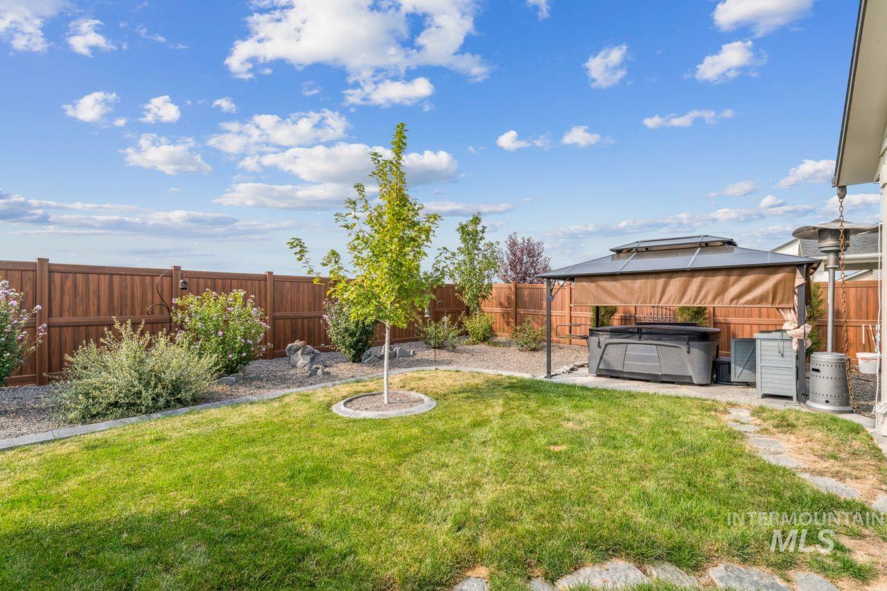 Fenced backyard featuring a hot tub, a gazebo, and a patio