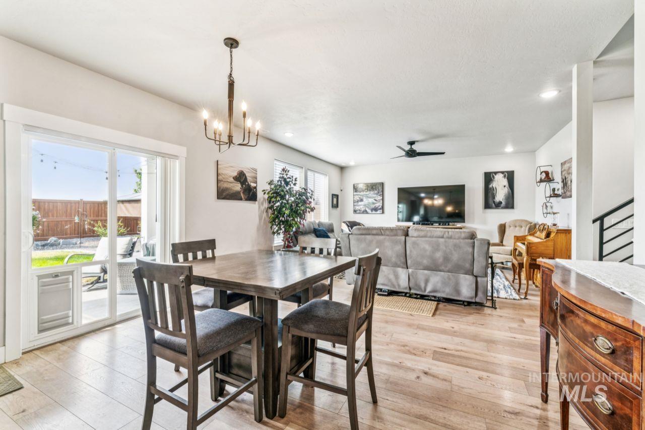 Dining area featuring light wood finished floors, a ceiling fan, a chandelier, recessed lighting, and stairway