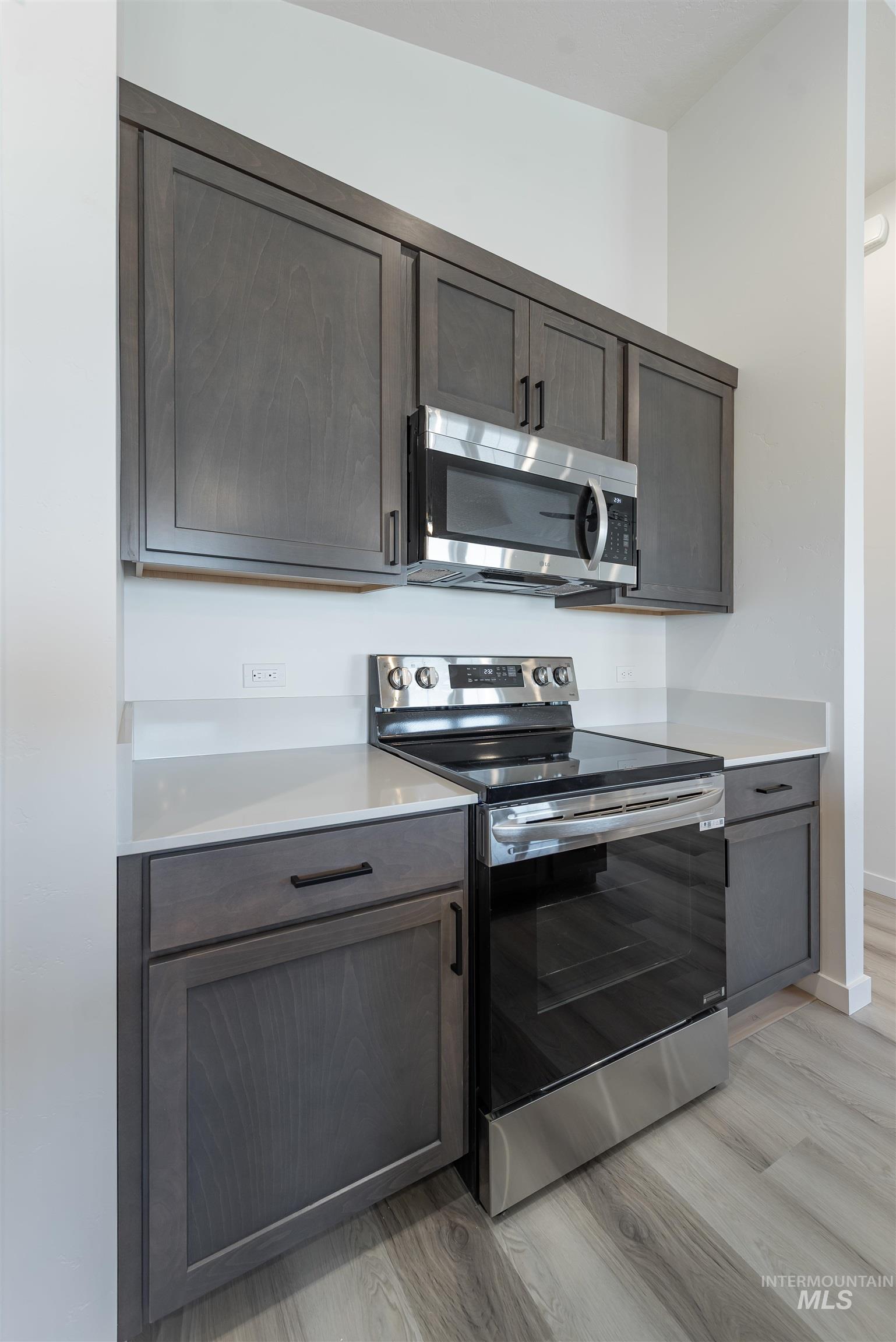Kitchen featuring stainless steel appliances, light wood finished floors, and dark brown cabinetry