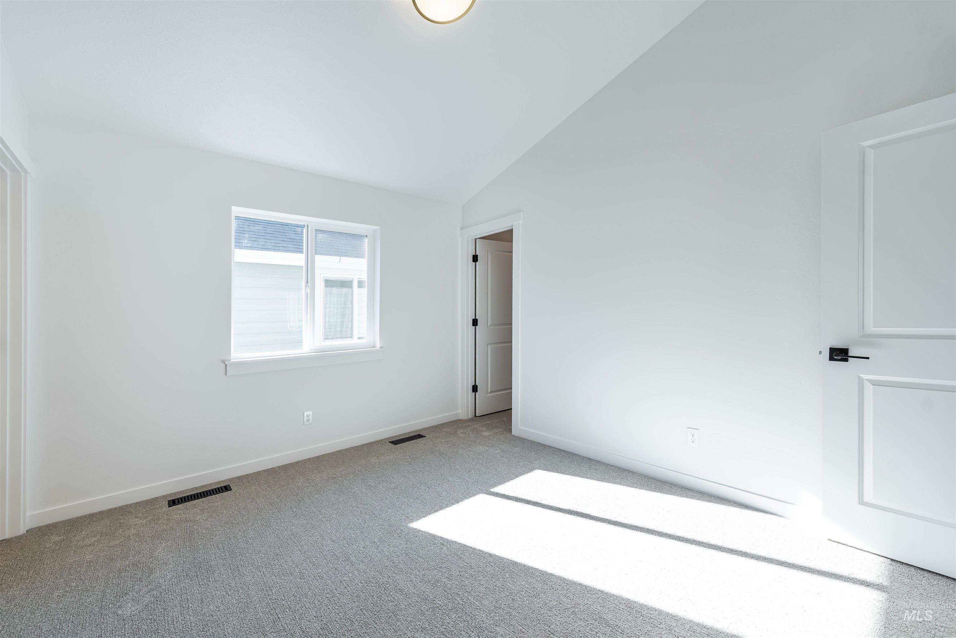 Unfurnished bedroom with vaulted ceiling and carpet flooring