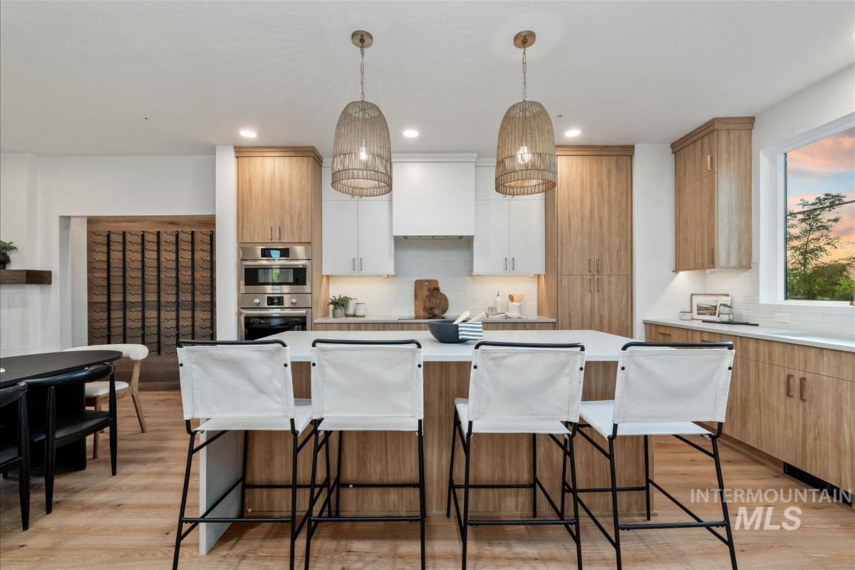 Kitchen featuring light wood-style flooring, tasteful backsplash, a breakfast bar, and recessed lighting