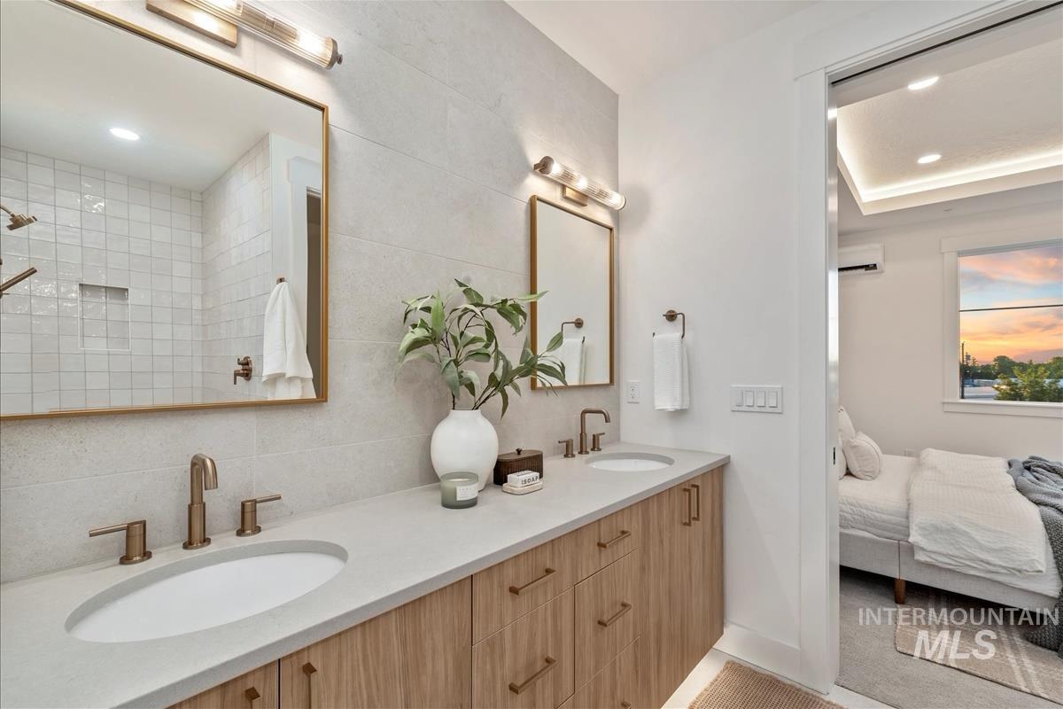Bathroom with recessed lighting, double vanity, ensuite bath, tasteful backsplash, and tile walls