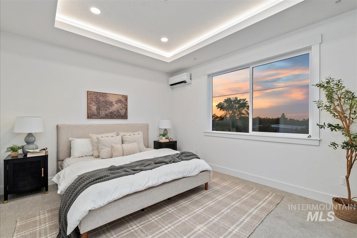 Bedroom featuring carpet flooring, a tray ceiling, recessed lighting, and a wall mounted AC