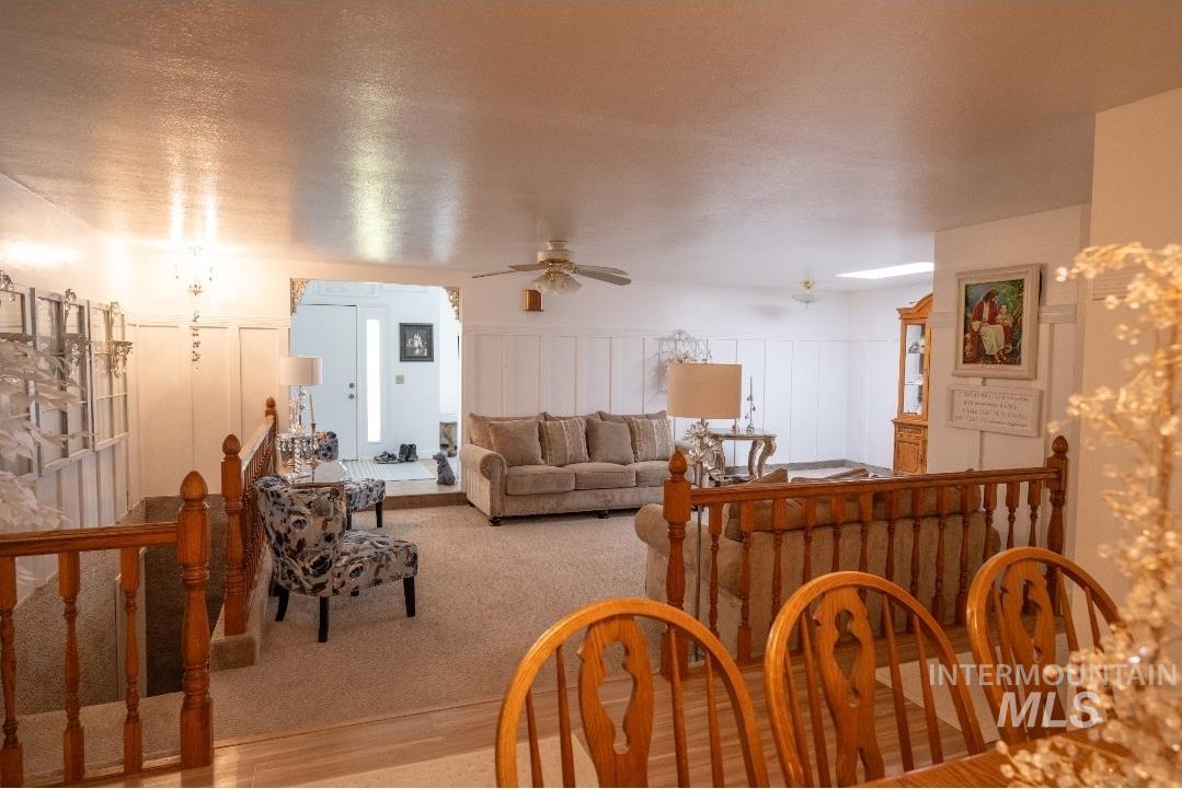 Living room with a ceiling fan, wood finished floors, and a decorative wall