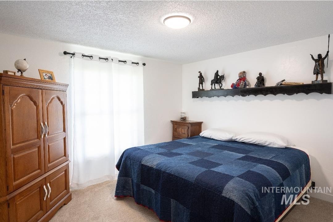 Bedroom featuring light colored carpet and a textured ceiling