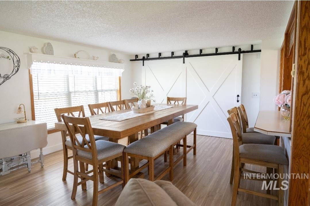 Dining room with a barn door, a textured ceiling, and wood finished floors
