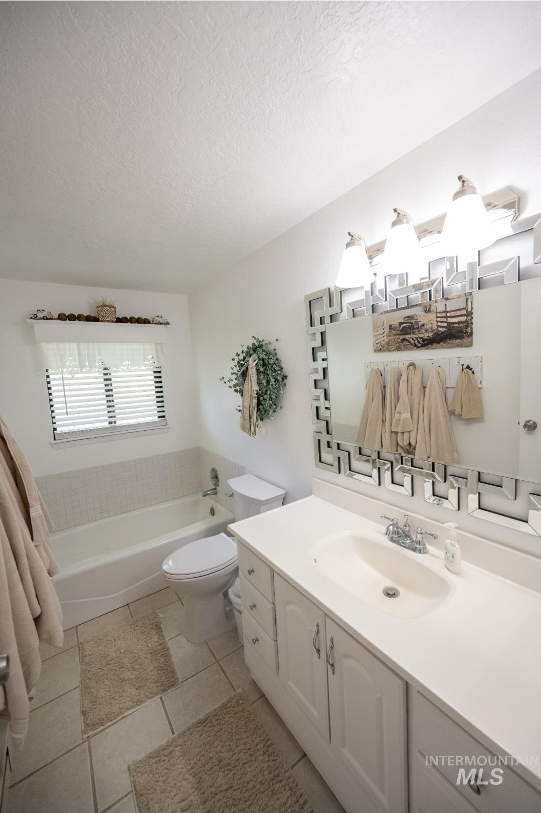 Full bathroom with a garden tub, vanity, a textured ceiling, and light tile patterned floors