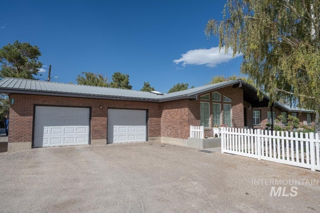 Ranch-style house featuring brick siding, driveway, and a metal roof