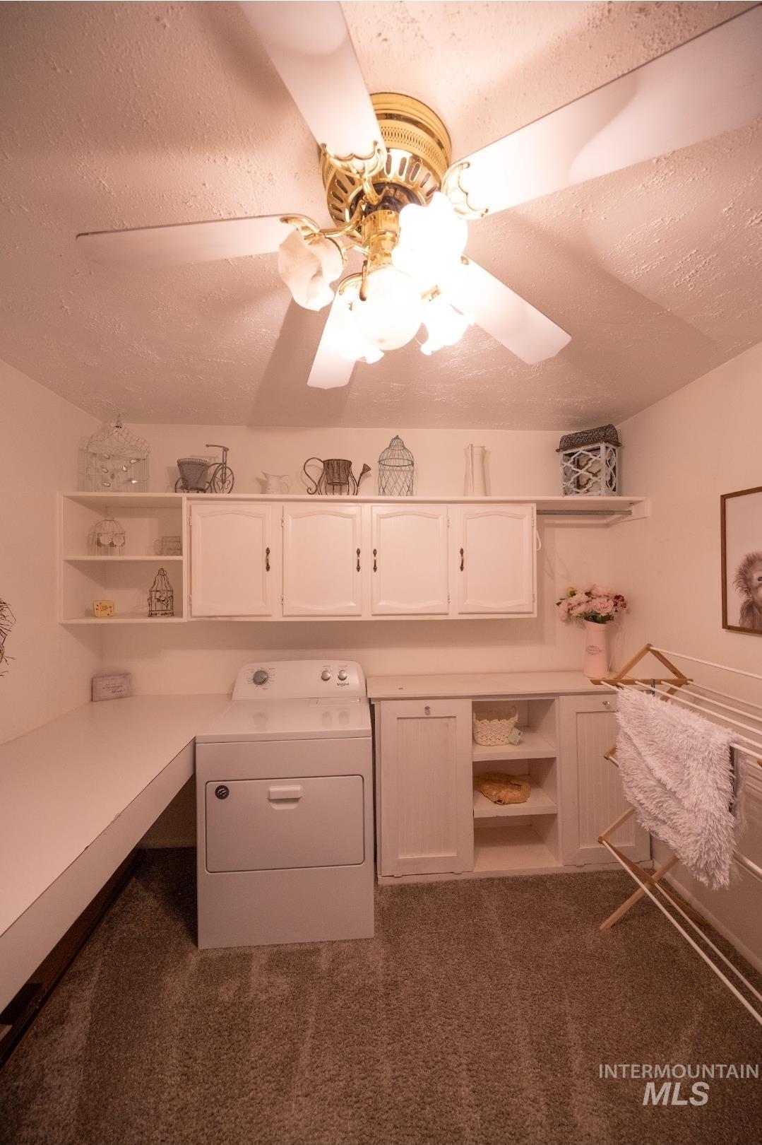 Unfurnished office featuring washer / dryer, a textured ceiling, and dark carpet
