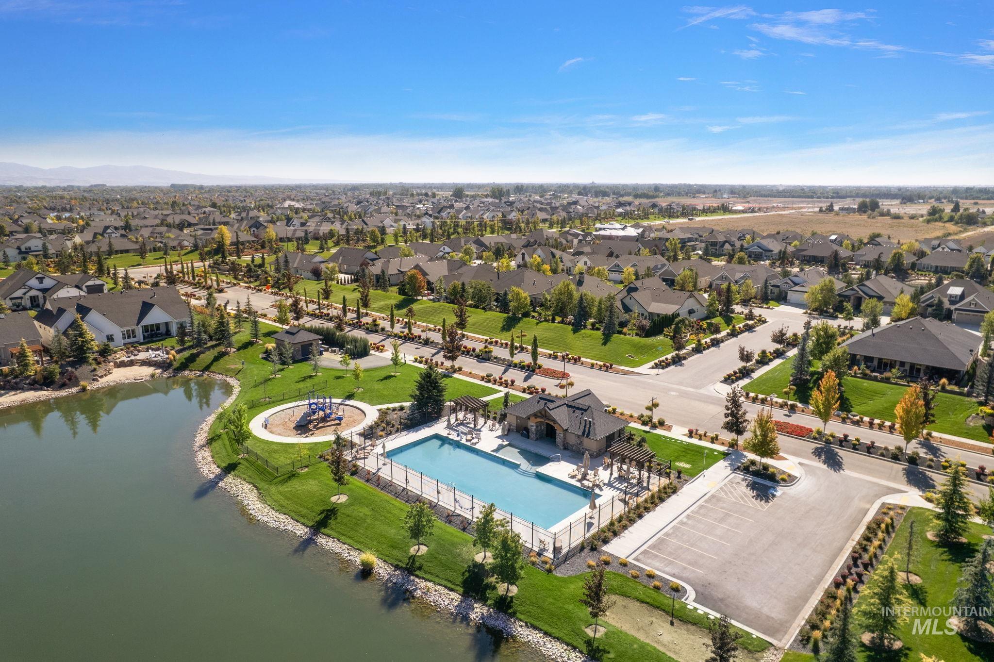 Aerial perspective of suburban area featuring a pool and a nearby body of water