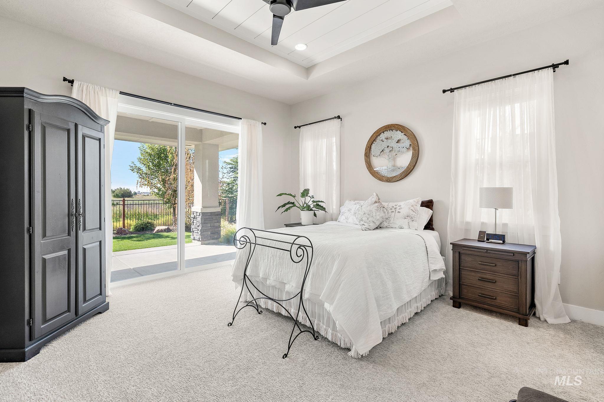 Bedroom with a tray ceiling, light colored carpet, access to outside, ceiling fan, and recessed lighting