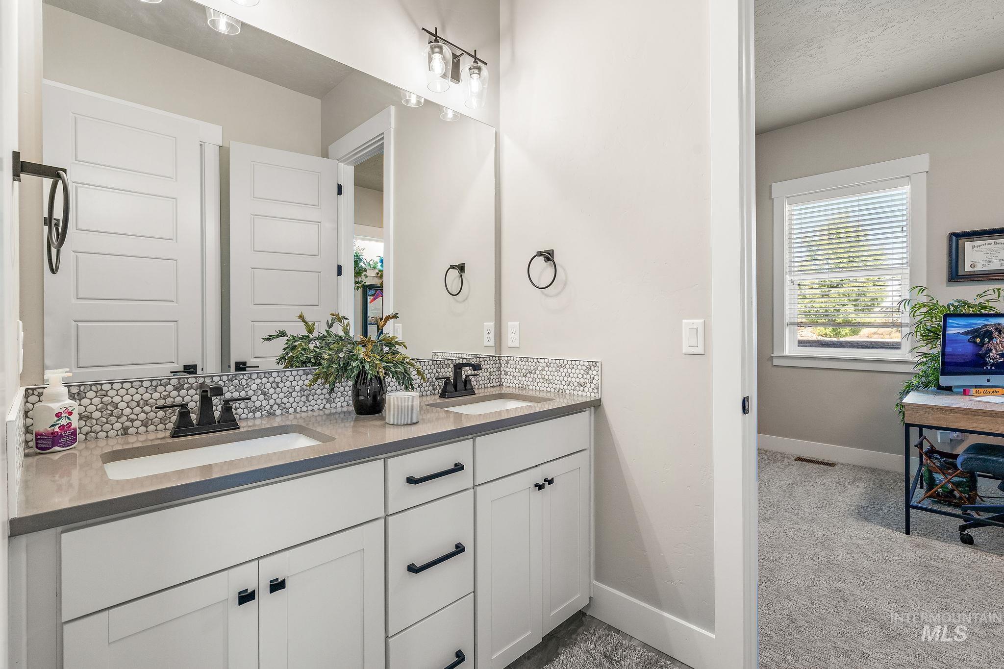 Full bathroom with tasteful backsplash, double vanity, healthy amount of natural light, and a textured ceiling