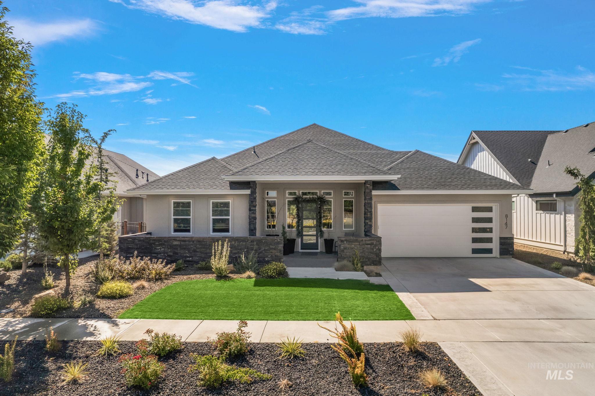View of front of home with a shingled roof, stone siding, driveway, and an attached garage