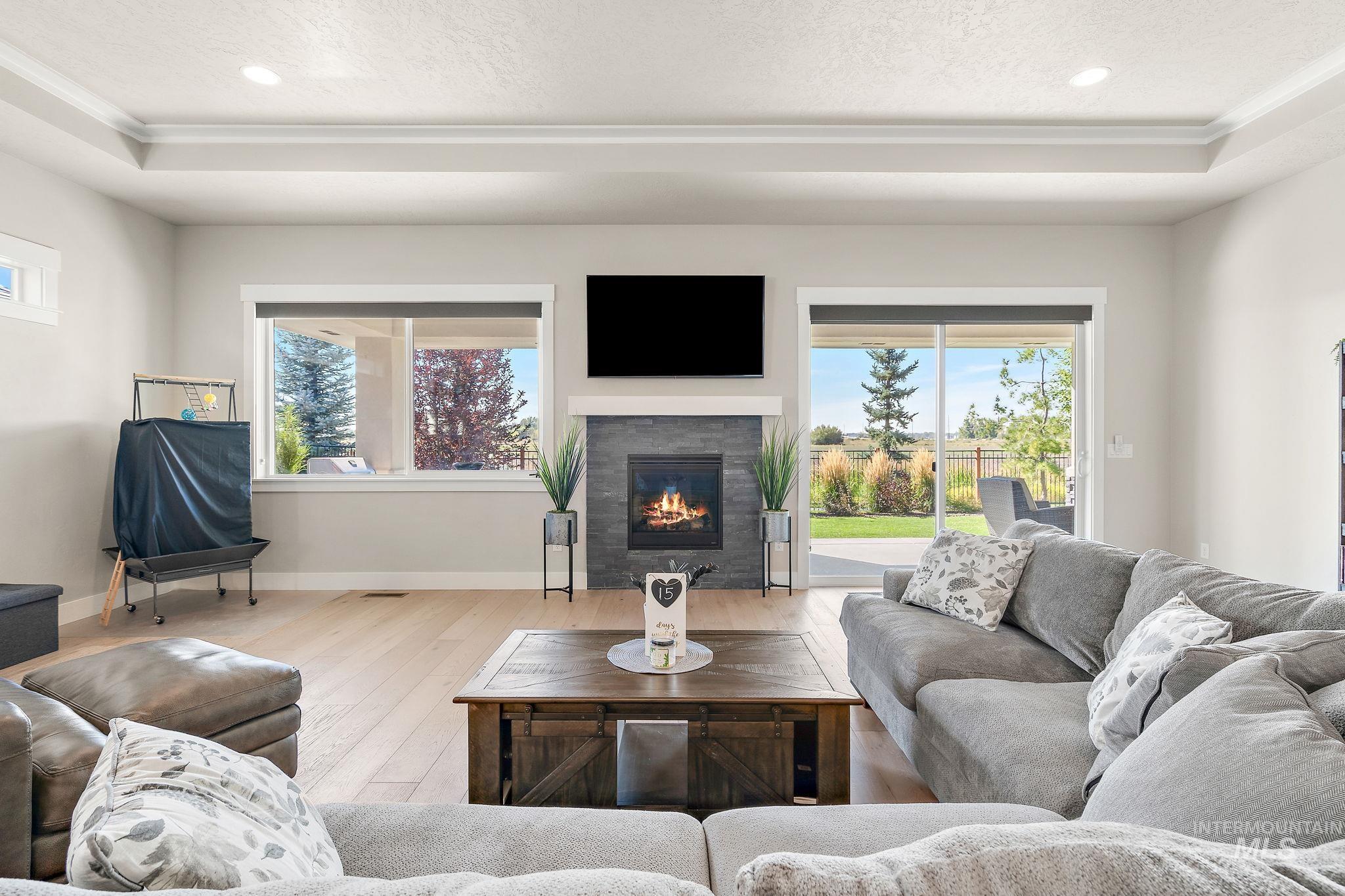 Living room with a tray ceiling, recessed lighting, hardwood / wood-style floors, a tiled fireplace, and a textured ceiling
