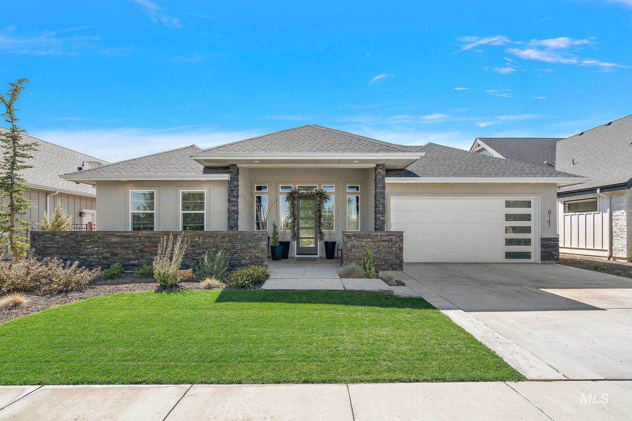 Prairie-style home featuring roof with shingles, a front lawn, stone siding, driveway, and stucco siding