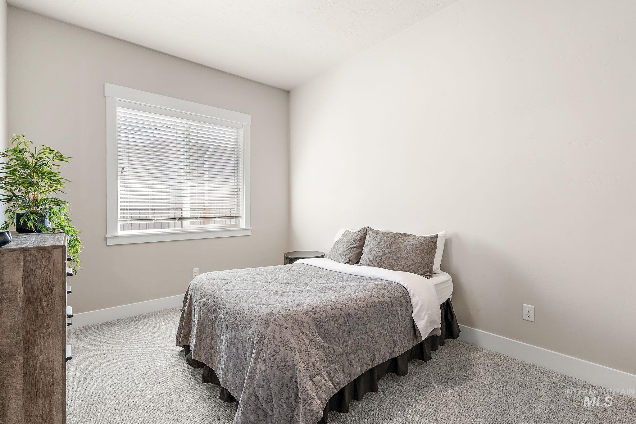 Bedroom with light colored carpet and baseboards