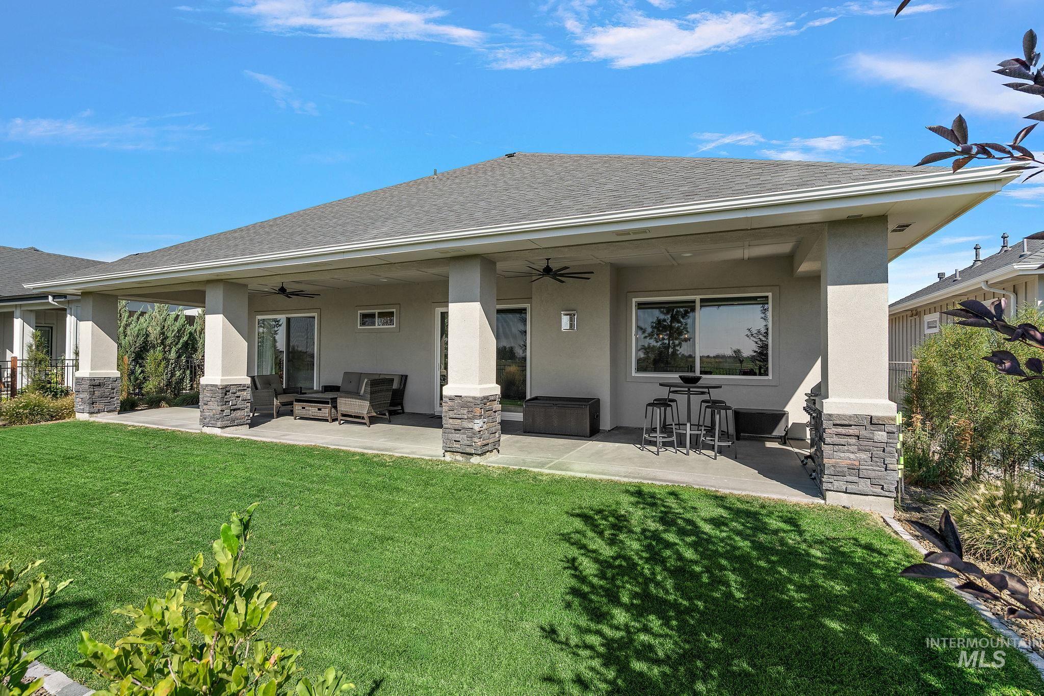 Rear view of property featuring stucco siding, a patio, and a yard