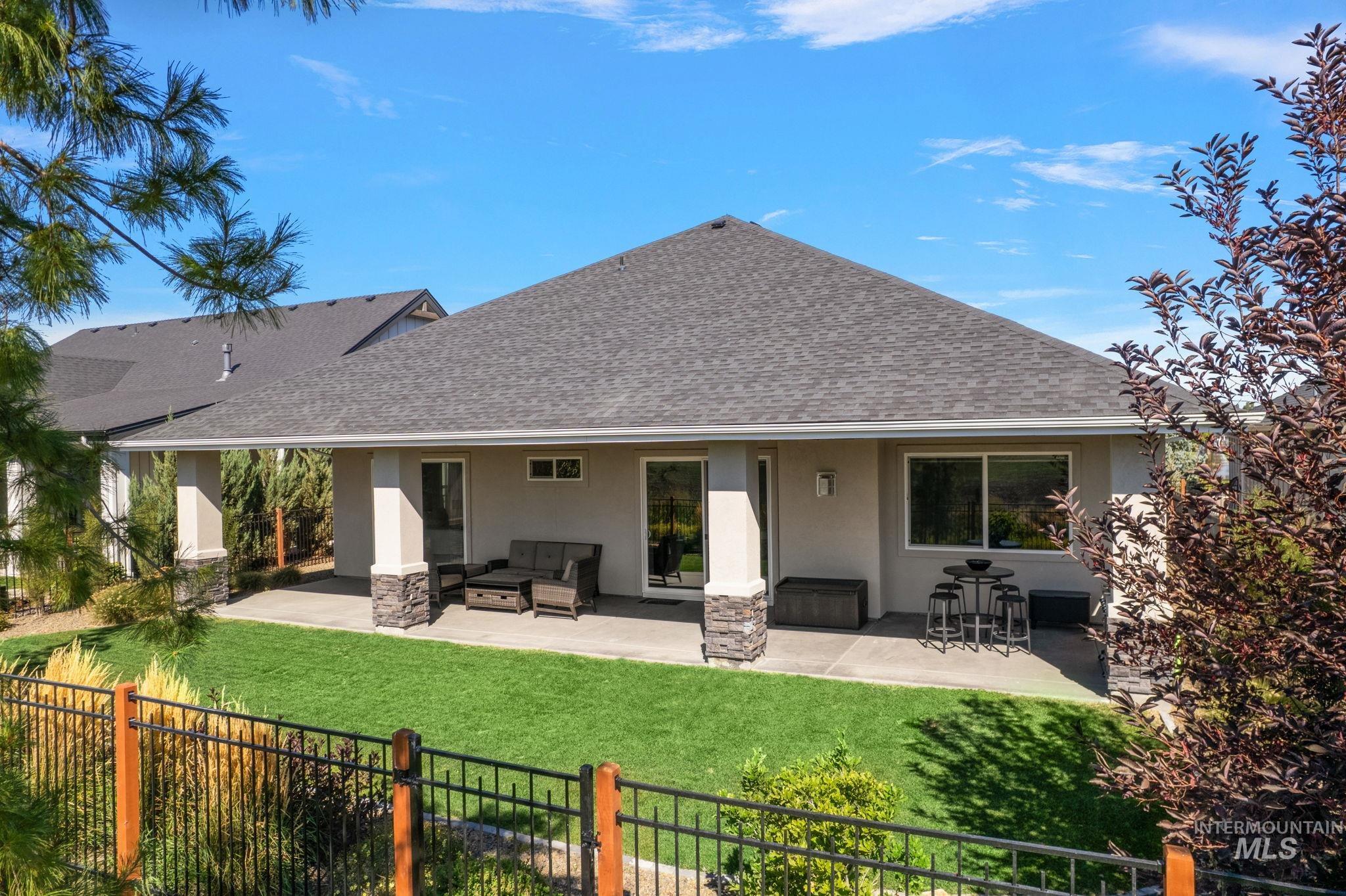 Rear view of property featuring a shingled roof, stucco siding, and a patio