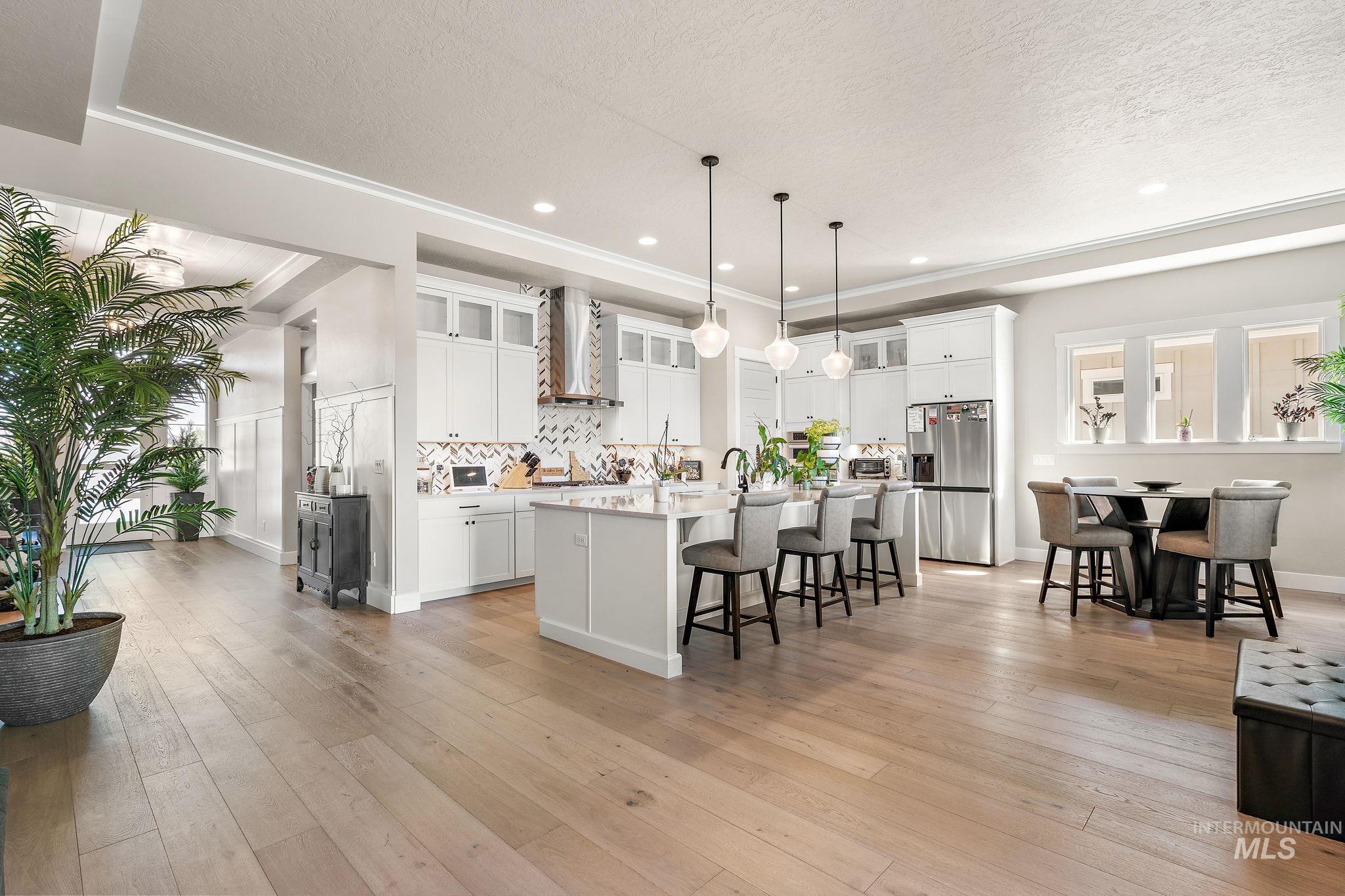 Kitchen with white cabinetry, a kitchen breakfast bar, light wood-style flooring, a kitchen island with sink, and a textured ceiling