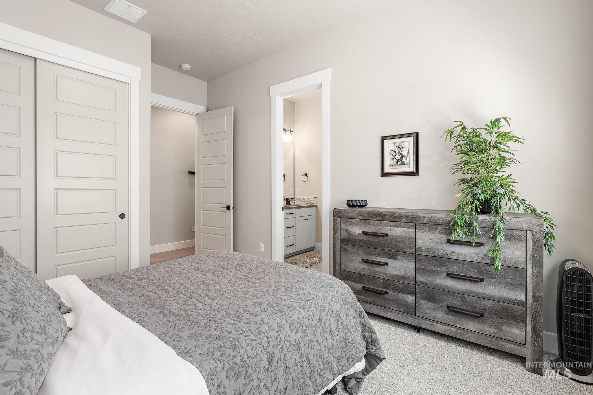 Bedroom with light colored carpet, a closet, and connected bathroom