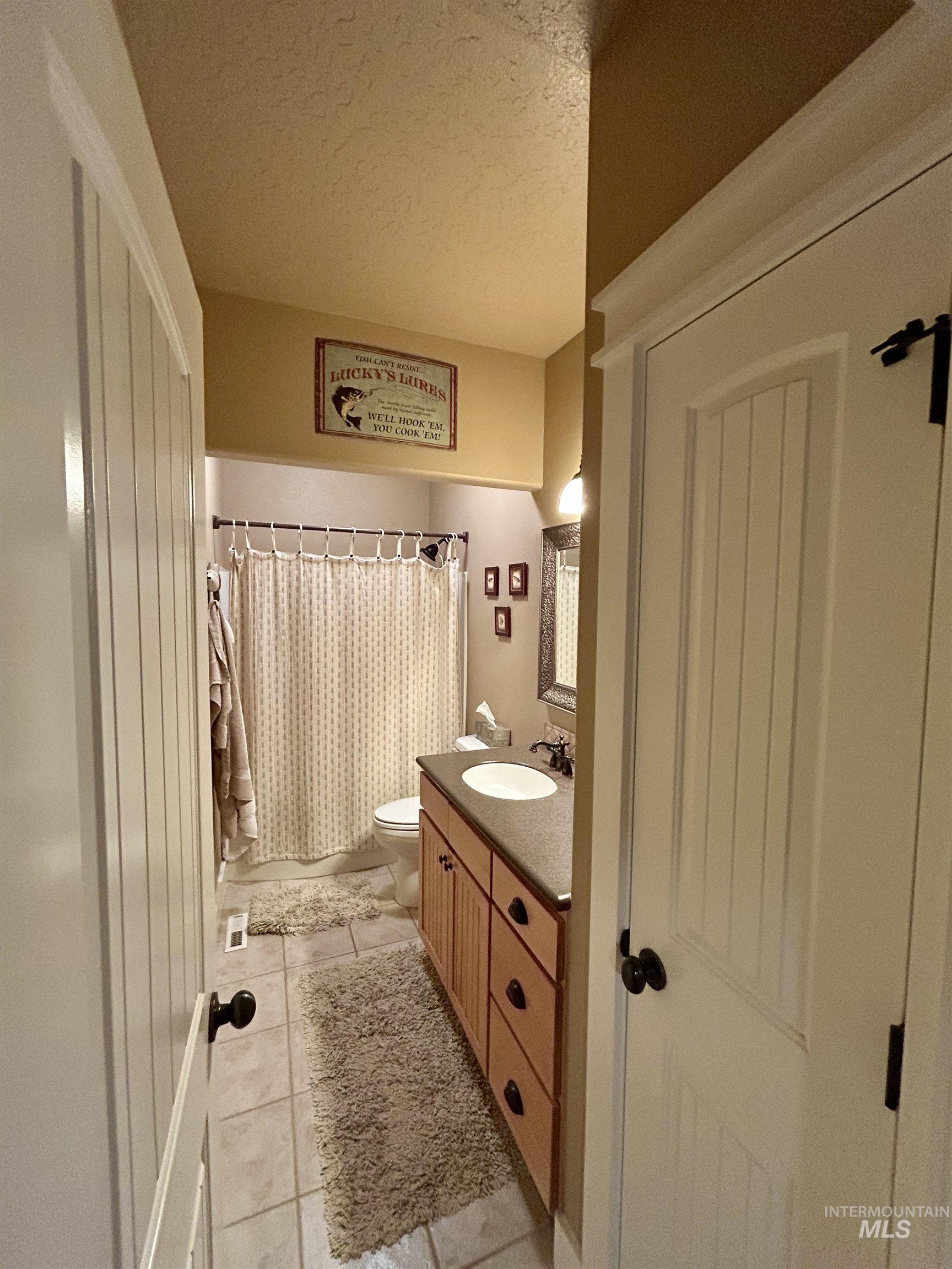 Bathroom with vanity, a textured ceiling, curtained shower, and tile patterned floors