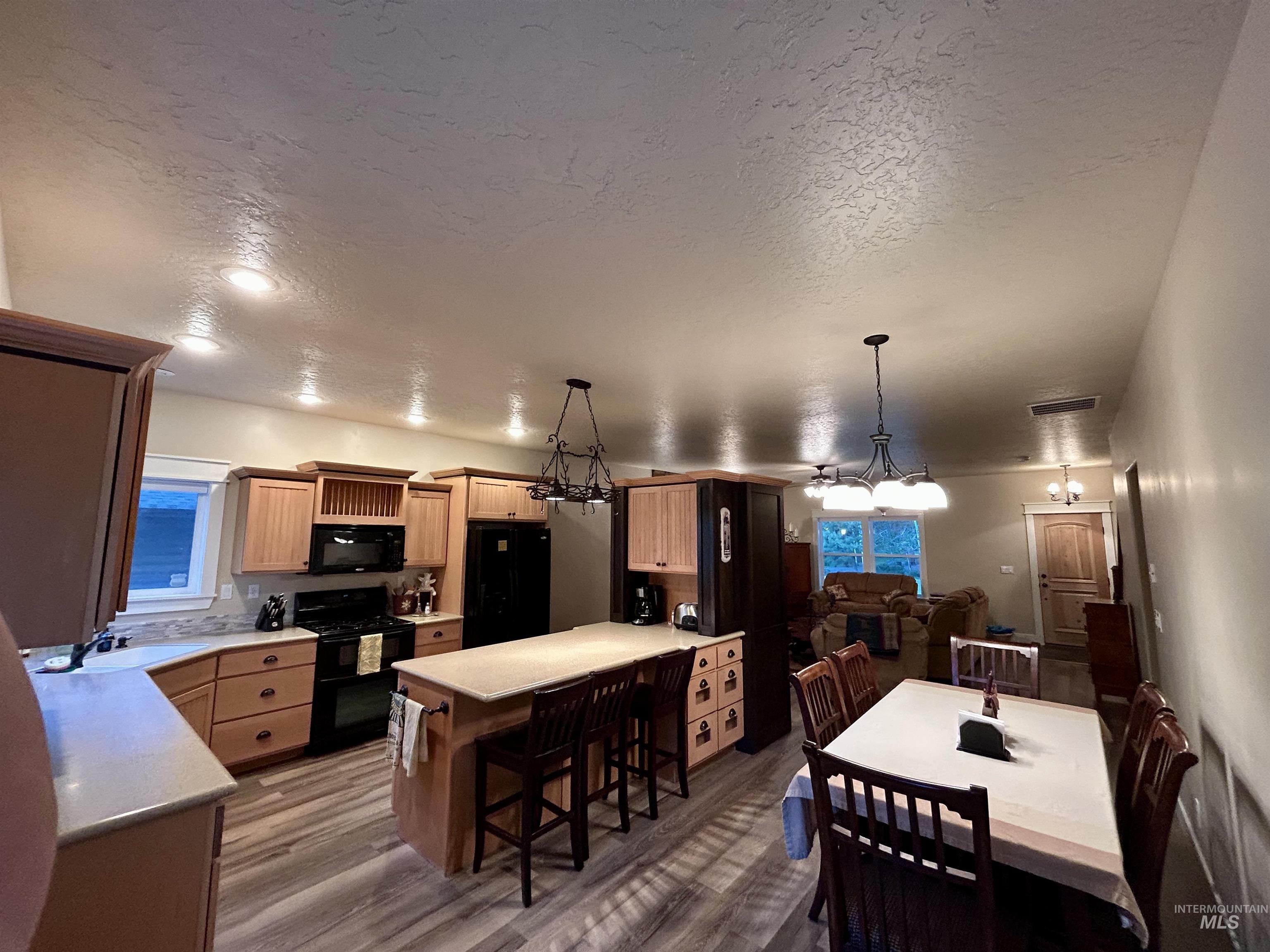 Dining space with a textured ceiling, light wood finished floors, and a chandelier