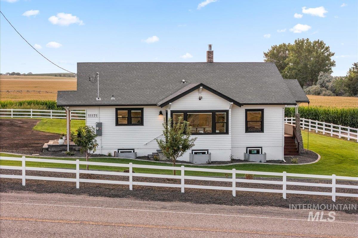 View of front of property with a view of countryside, a chimney, and a shingled roof